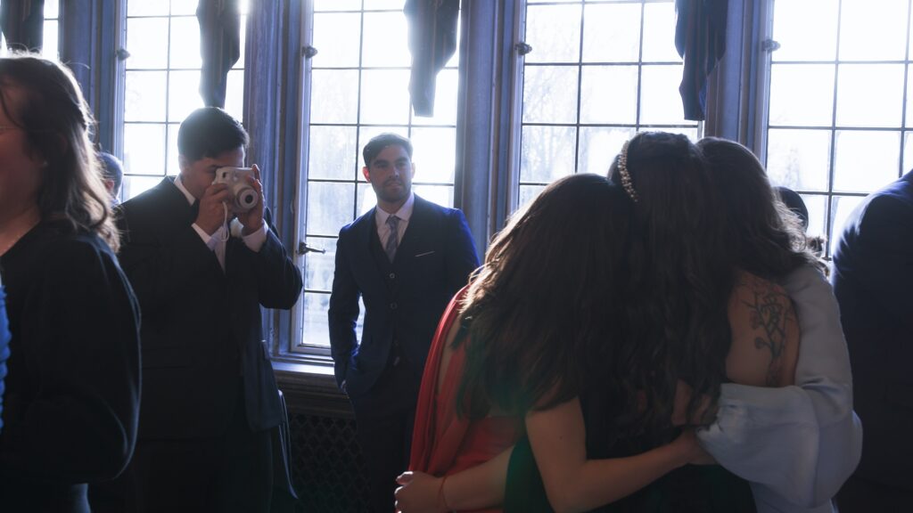 Wedding guests sharing a candid moment during cocktail hour while a Polaroid photo is taken.